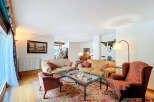 Luxurious living room with hardwood floors, featuring two beige sofas, a red armchair, and an ornate area rug.