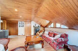 Cozy attic living space with wood-paneled ceilings and hardwood floors.