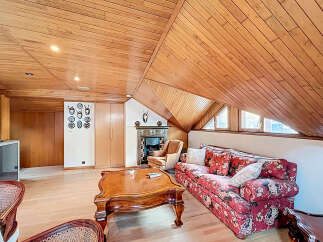 Cozy attic living space with wood-paneled ceilings and hardwood floors.