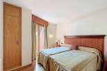 This charming bedroom boasts twin beds dressed in beige linens, complemented by a rich, patterned headboard.