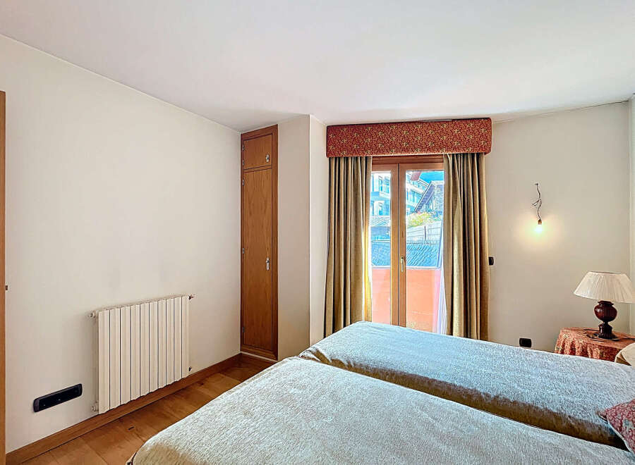 Bright bedroom with twin beds, offering stunning mountain views from its private balcony.