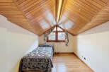 Charming attic bedroom with wood-paneled ceiling and hardwood floors.