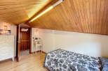 Charming attic bedroom with wood-paneled ceiling and hardwood floors.