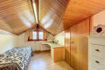 Charming attic bedroom with wooden beams, built-in desk, and ample storage.