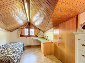 Charming attic bedroom with wooden beams, built-in desk, and ample storage.