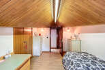 Charming attic bedroom with wood-paneled ceiling, built-in storage, and hardwood floors.