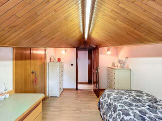 Charming attic bedroom with wood-paneled ceiling, built-in storage, and hardwood floors.