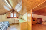 Charming attic room with wooden beams, built-in desk, and cozy sofa nook.