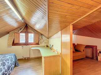 Charming attic room with wooden beams, built-in desk, and cozy sofa nook.