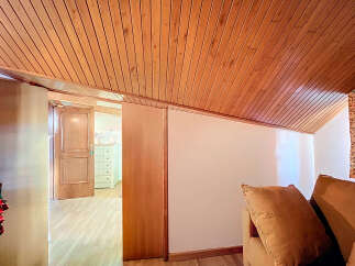 Discover this charming attic room featuring a wood paneled ceiling and ample natural light.