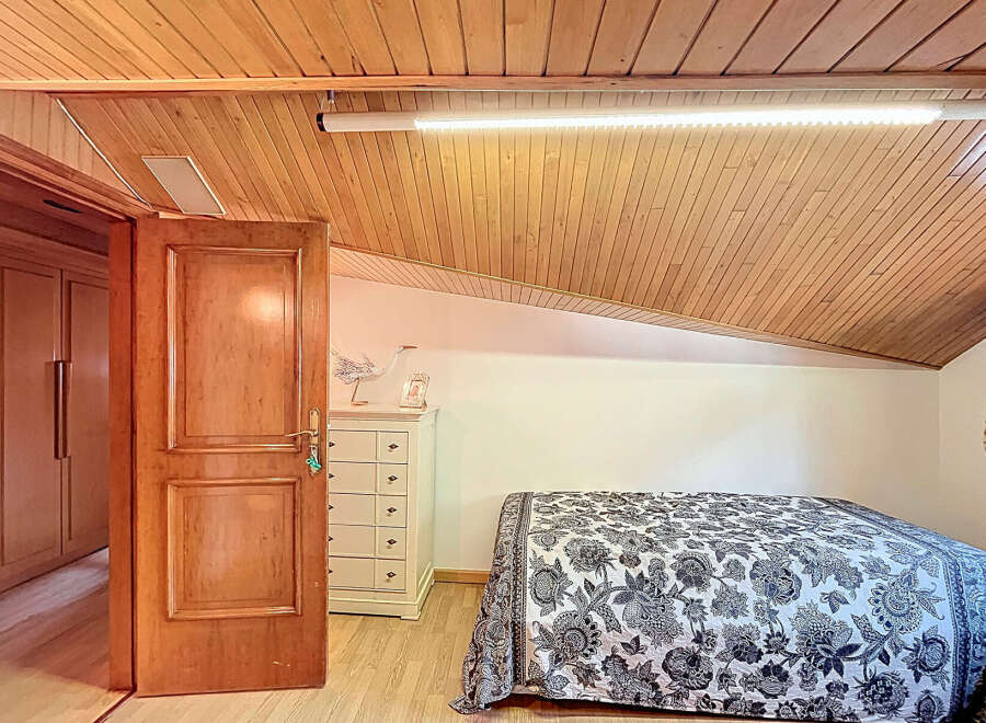Charming attic bedroom with wooden ceiling and built-in wardrobe.