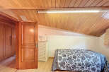 Charming attic bedroom with wooden ceiling and built-in wardrobe.