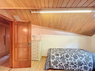 Charming attic bedroom with wooden ceiling and built-in wardrobe.