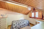 Charming attic bedroom with wood-paneled ceiling and sloped walls.