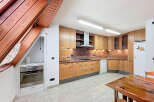 This charming kitchen boasts a unique sloped ceiling with wood paneling, adding character and warmth to the space.