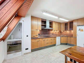 This charming kitchen boasts a unique sloped ceiling with wood paneling, adding character and warmth to the space.
