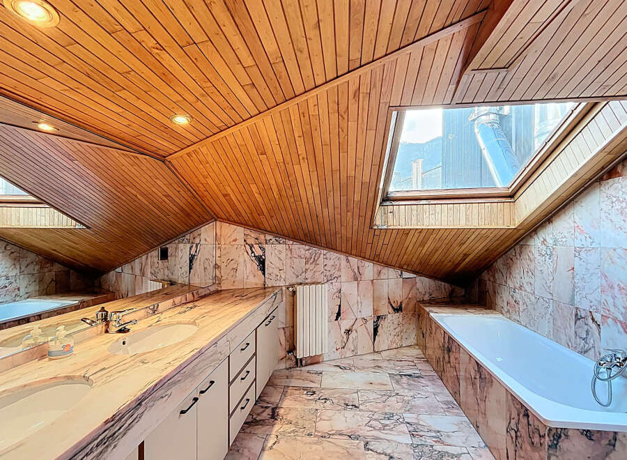 Luxurious bathroom with marble finishes and wooden ceilings.