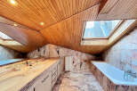 Luxurious bathroom with marble finishes and wooden ceilings.