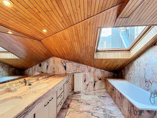 Luxurious bathroom with marble finishes and wooden ceilings.