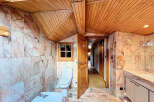 This stunning bathroom boasts a unique blend of rustic wood ceilings and elegant marble tiling, creating a luxurious and inviting atmosphere.