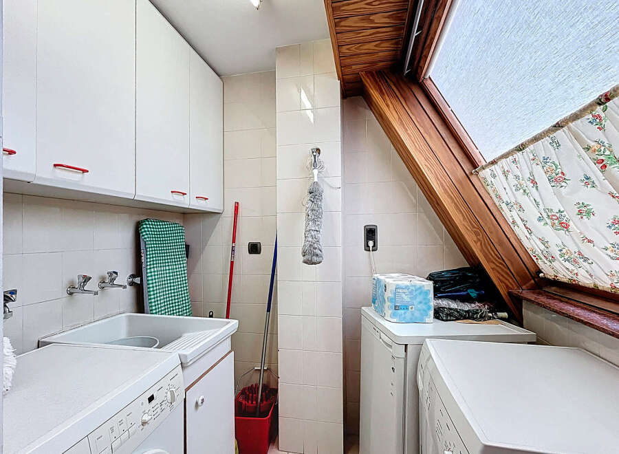 This charming laundry room boasts ample storage with white cabinets and a convenient built-in sink.