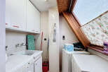 This charming laundry room boasts ample storage with white cabinets and a convenient built-in sink.