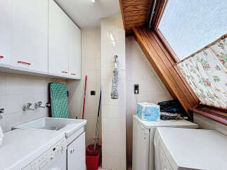This charming laundry room boasts ample storage with white cabinets and a convenient built-in sink.