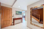 Elegant entrance hall with hardwood floors, a wooden console table, and a large ornate mirror reflecting a staircase.