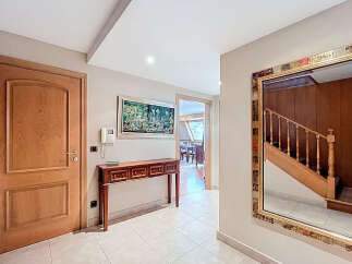 Elegant entrance hall with hardwood floors, a wooden console table, and a large ornate mirror reflecting a staircase.