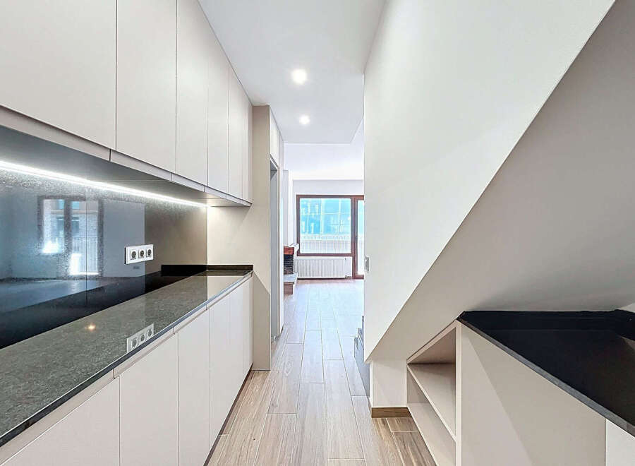 This modern kitchen features sleek, minimalist design with ample storage and a stunning black countertop.