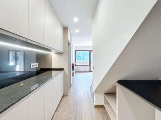 This modern kitchen features sleek, minimalist design with ample storage and a stunning black countertop.