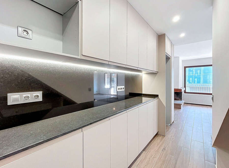 This modern kitchen boasts sleek, minimalist design with ample storage and a stunning countertop.