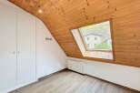 This charming attic room features a unique sloped ceiling with warm wooden paneling, creating a cozy and inviting atmosphere.