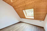 This charming room features a unique sloped ceiling with warm wooden paneling, creating a cozy and inviting atmosphere.
