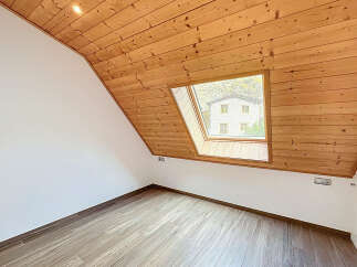This charming room features a unique sloped ceiling with warm wooden paneling, creating a cozy and inviting atmosphere.