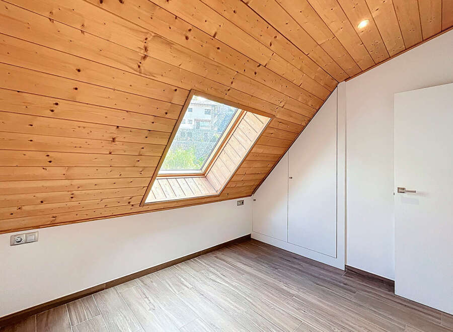 Discover the charm of this unique attic space, featuring a stunning wooden sloped ceiling and a skylight that floods the room with natural light.