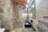 Experience luxury in this stunning bathroom featuring exquisite stone tile work and a sleek black sink.