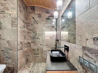 Experience luxury in this stunning bathroom featuring exquisite stone tile work and a sleek black sink.
