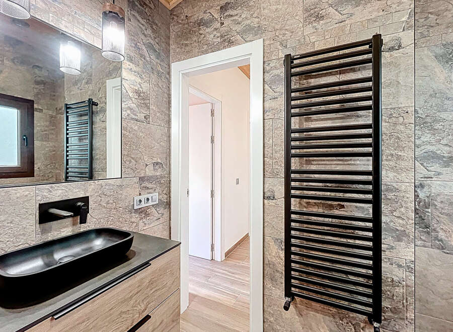 This modern bathroom features a sleek black sink and faucet, complemented by a stylish black towel warmer.