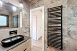 This modern bathroom features a sleek black sink and faucet, complemented by a stylish black towel warmer.