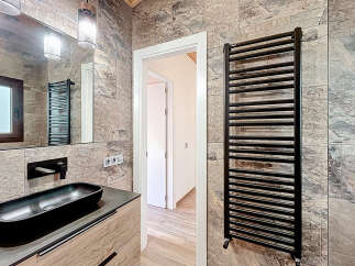 This modern bathroom features a sleek black sink and faucet, complemented by a stylish black towel warmer.
