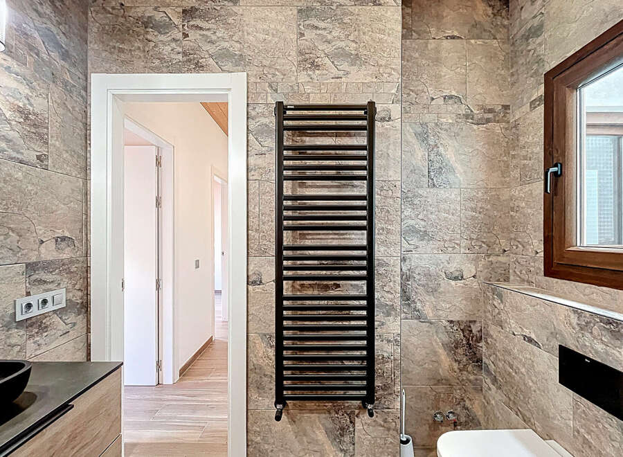Step into a beautifully designed bathroom featuring a modern black towel warmer, adding both style and functionality.