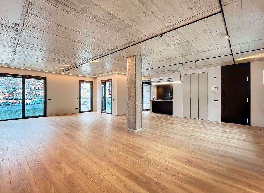 Stunning open-plan living space with exposed concrete ceilings and sleek modern finishes.