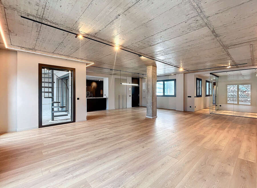 Stunning open-plan living space with exposed concrete ceilings and sleek modern finishes.
