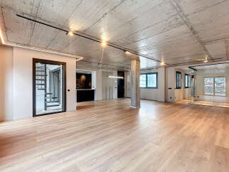Stunning open-plan living space with exposed concrete ceilings and sleek modern finishes.