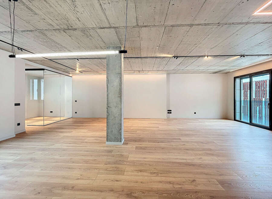 Stunning open-plan living space with exposed concrete ceilings and sleek modern lighting.