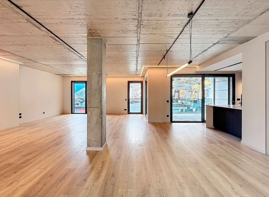 Stunning open-plan living space with exposed concrete ceilings and sleek modern finishes.