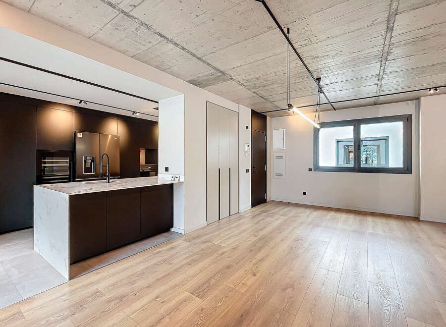 Stunning modern apartment boasts an open-plan living area with sleek dark kitchen and island, complemented by light oak flooring.