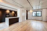 Stunning modern apartment boasts an open-plan living area with sleek dark kitchen and island, complemented by light oak flooring.