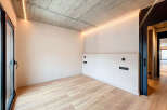 Modern minimalist room with concrete ceiling, LED lighting, and light oak wood flooring.